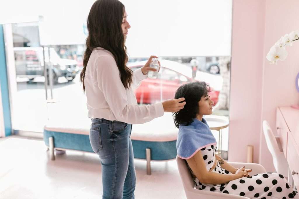 Cabeleireira a pentear o cabelo de uma cliente num salão moderno