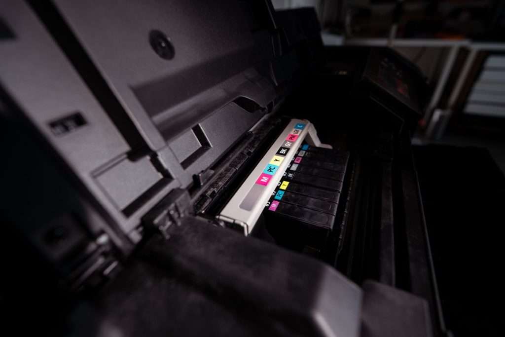 Impressora aberta com cartuchos de tinta de várias cores (CMYK) alinhados