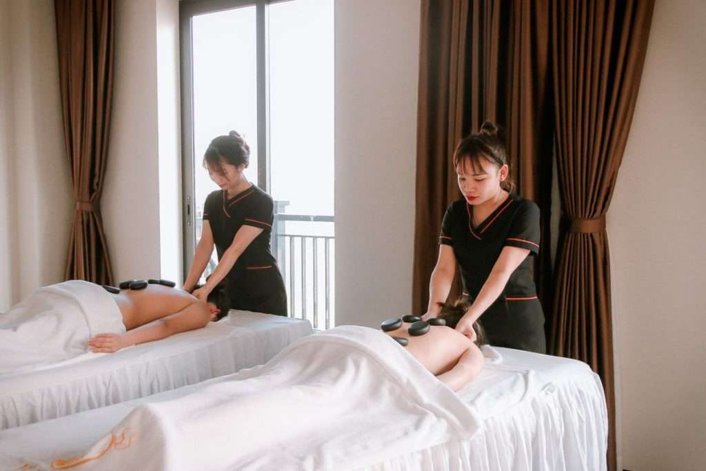 Duas profissionais a fazer massagens com pedras quentes num spa