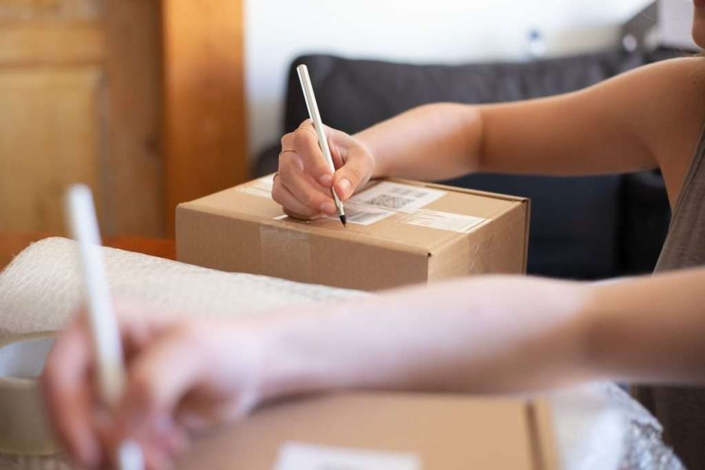 Mãos a embalar e a etiquetar uma caixa de encomenda