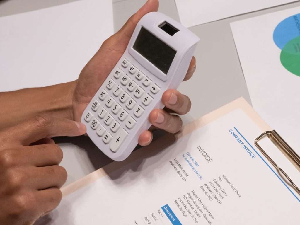 Mão a usar uma calculadora junto de uma fatura