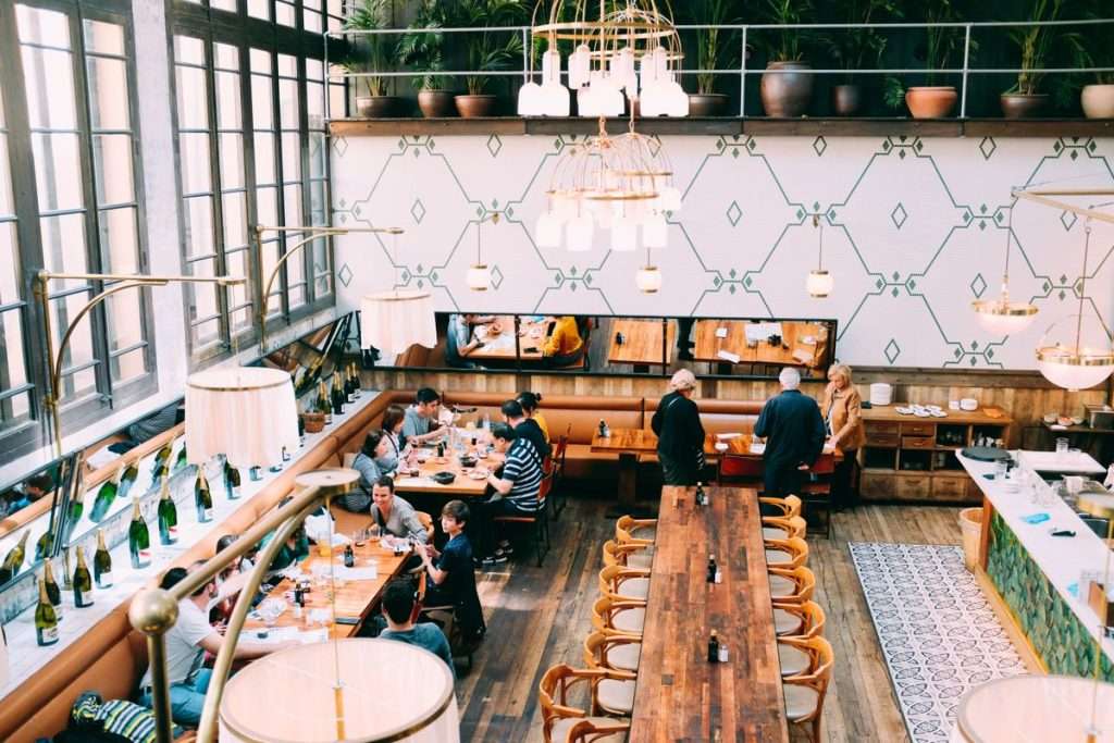 Interior de um restaurante amplo, com mesas de madeira e clientes a almoçar