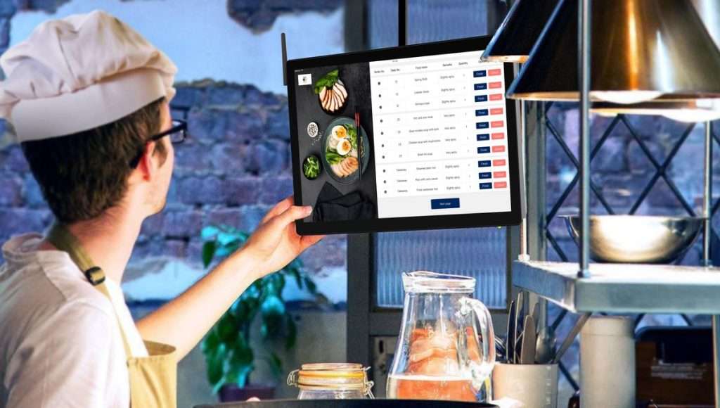 Cozinheiro a consultar os pedidos num ecrã tátil na cozinha de um restaurante